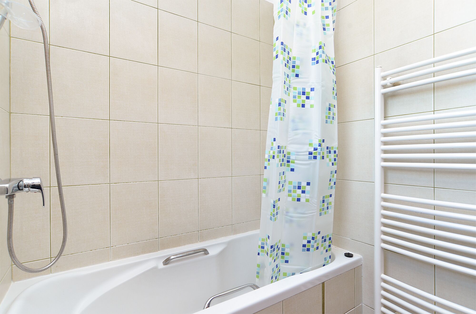 A bathroom with a bathtub, shower, and a towel rack.