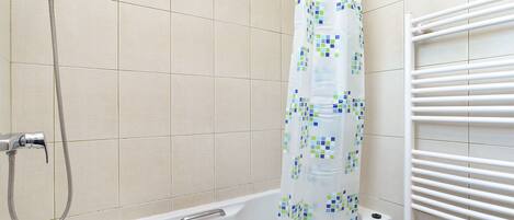 A bathroom with a bathtub, shower, and a towel rack.
