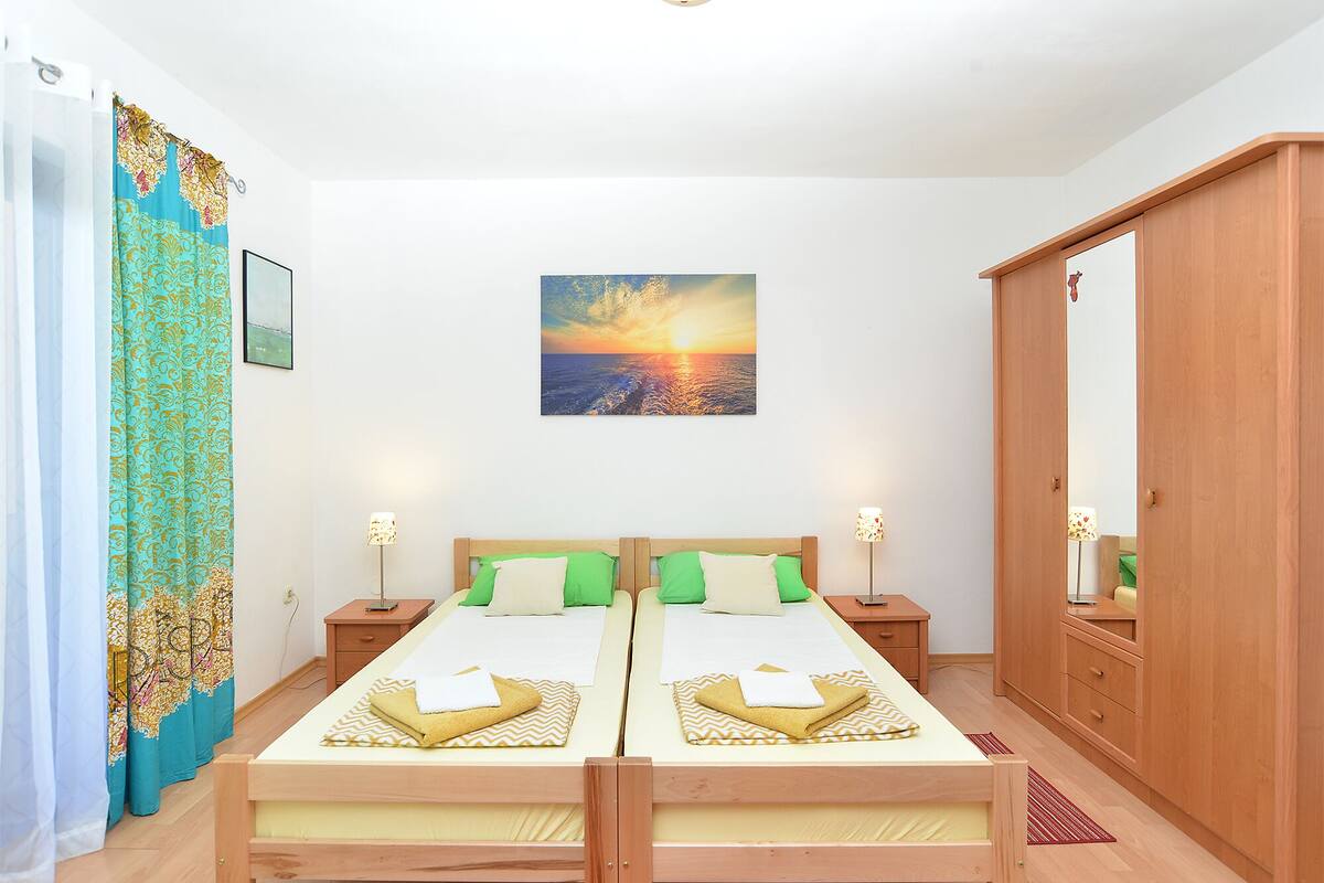 A double bed with two nightstands, a mirror, and a view of the sunset.