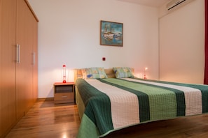 Una camera da letto con un letto, comodini, un quadro e pavimento in legno.