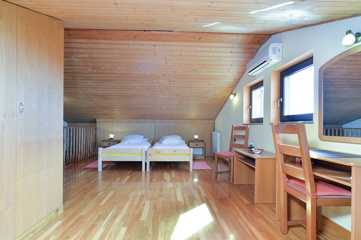 A bedroom with two beds, a desk, and a chair.
