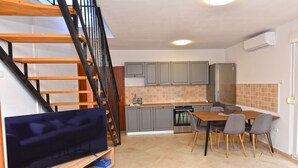 Cocina compacta con armarios grises, horno integrado y comedor con mesa y sillas.