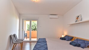 Un dormitorio con cama, una silla, una mesita de noche y una ventana.