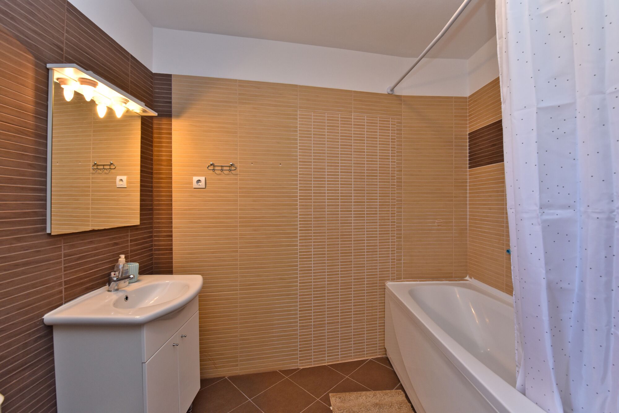 A bathroom with a sink, mirror, and bathtub.