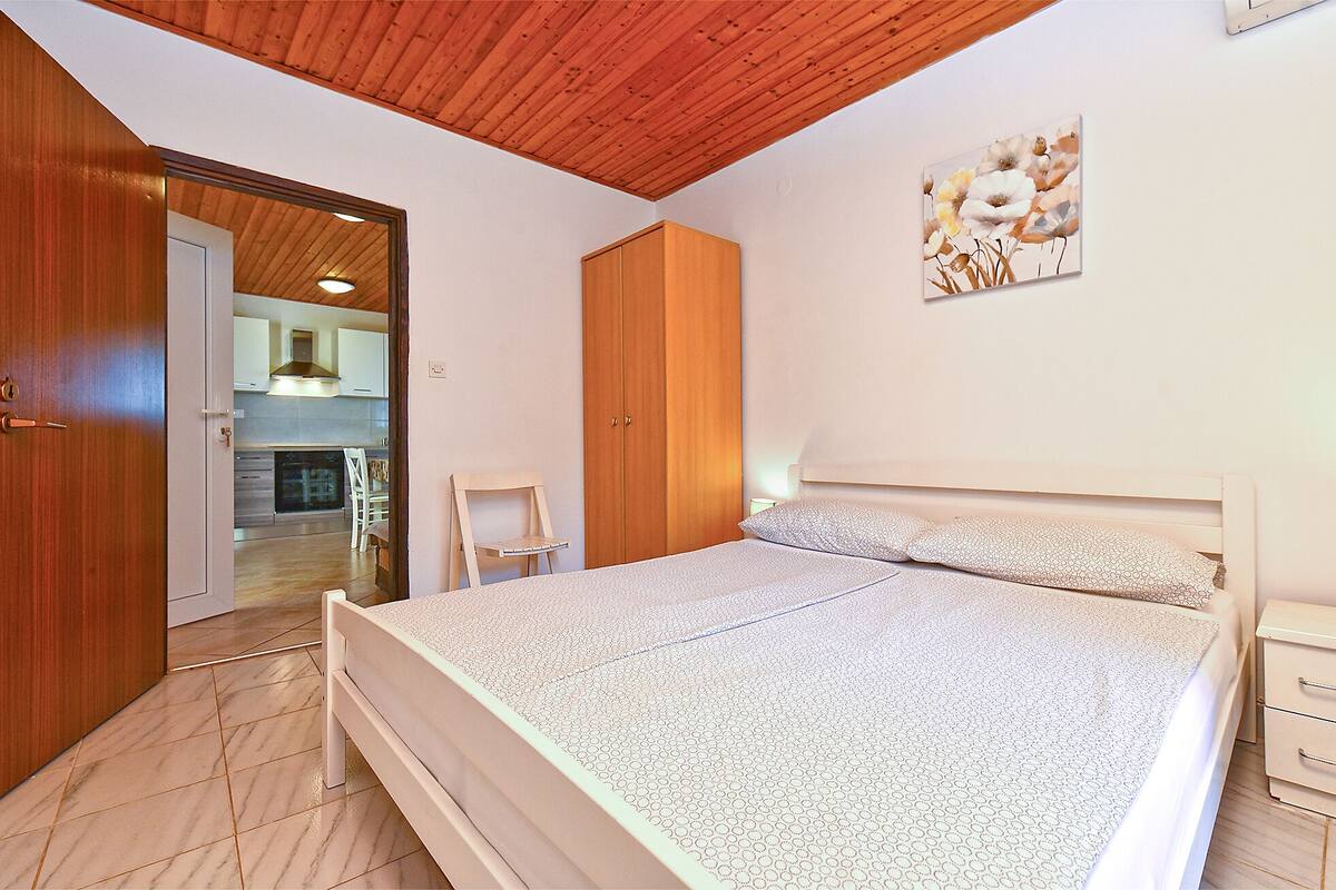 A bedroom with a bed, wooden wardrobe, and a painting on the wall.