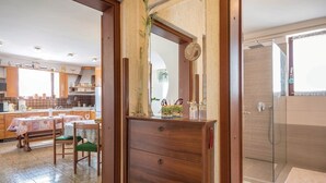 Una cocina moderna con armarios de madera, una mesa de comedor y vista al baño contiguo.