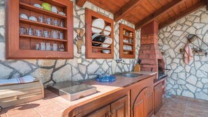 Una cocina rústica con paredes de piedra, estantes de madera y un horno empotrado.
