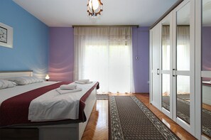 Une chambre à coucher comprenant un lit, une lampe de chevet, une fenêtre avec des rideaux et une porte-fenêtre coulissante donnant sur un balcon.