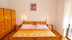 Ein Schlafzimmer mit einem hölzernen Bett, zwei Nachttischen, einem Schrank und einem Bild an der Wand.