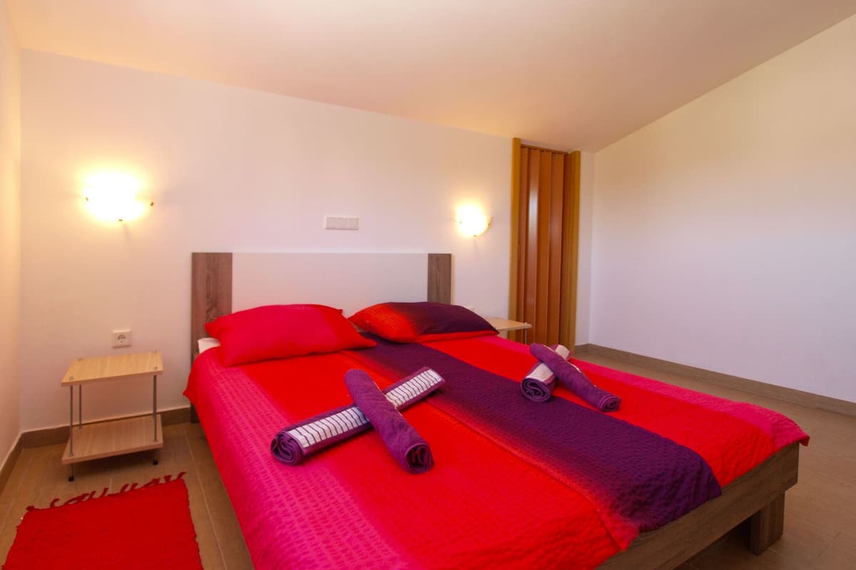 Ein modernes Schlafzimmer mit einem großen Bett, zwei Nachttischen und einem roten Teppich.