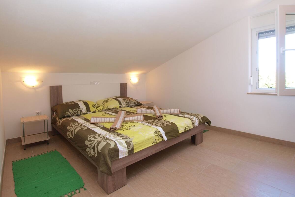 Ein Schlafzimmer mit einem Bett, zwei Nachttischlampen, einem grünen Teppich und einem Fenster.