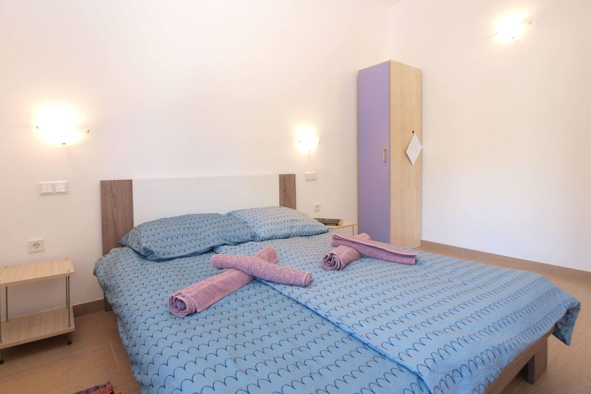 Ein Schlafzimmer mit einem Bett, zwei Nachttischen, einem Kleiderschrank und Wandleuchten.