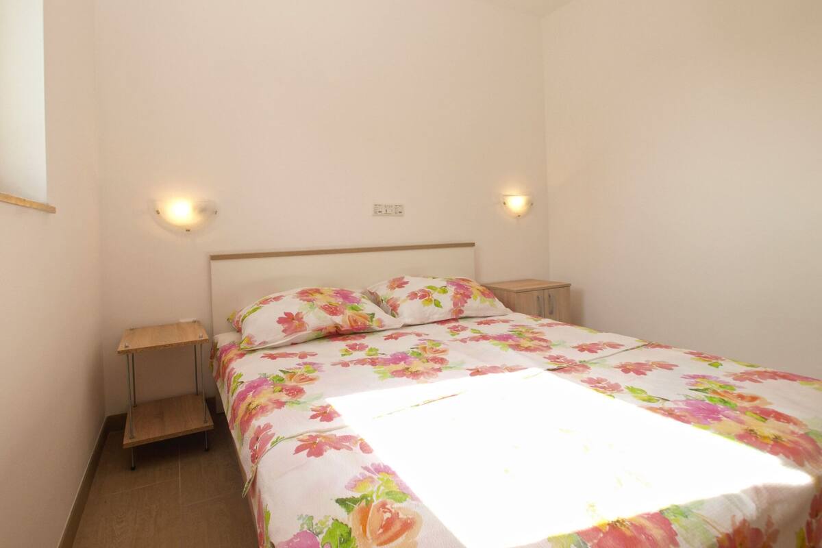 Ein Schlafzimmer mit einem Bett, zwei Nachttischen und einer Wandleuchte.