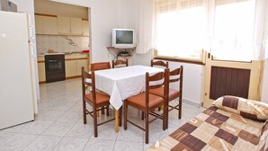 Una camera compatta con un tavolo da pranzo, sedie, un letto, una televisione e angolo cottura.