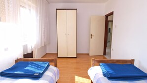 Una stanza con due letti, un armadio e un ingresso che porta in un'altra stanza.