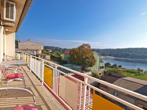 A balcony with chairs and a table, overlooking a body of water and a hilly landscape. - Apartments Susanne 79 (Pula)