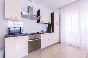 A modern kitchen with white cabinets, a built-in oven, and a microwave.