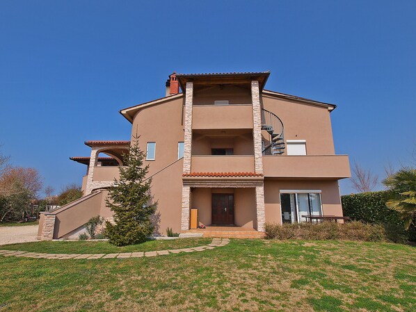A multi-story house with a stone facade, a central entrance, and a spiral staircase to the upper floor.