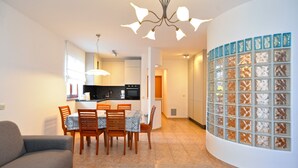 Una sala de estar moderna con un sofá, una mesa de comedor con sillas y una cocina al fondo.