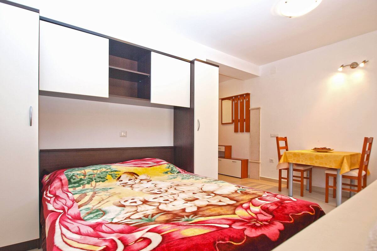 A bedroom with a bed, a small table, and a chair.