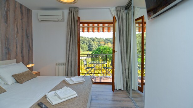 Un dormitorio con cama, mesita de noche y vistas a un balcón con sillas y una mesa.