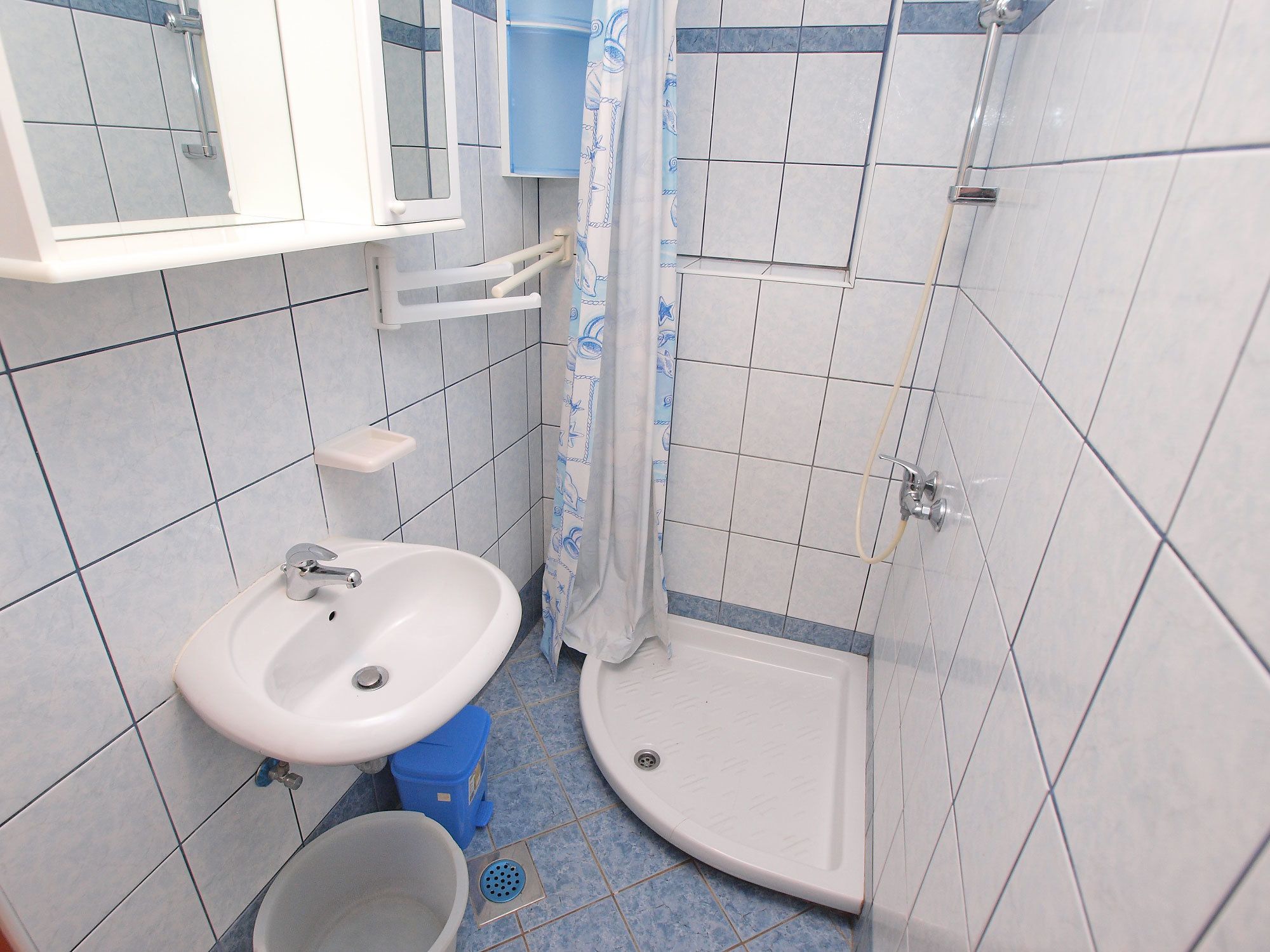 Une petite salle de bain avec un lavabo blanc, des toilettes et un espace douche.