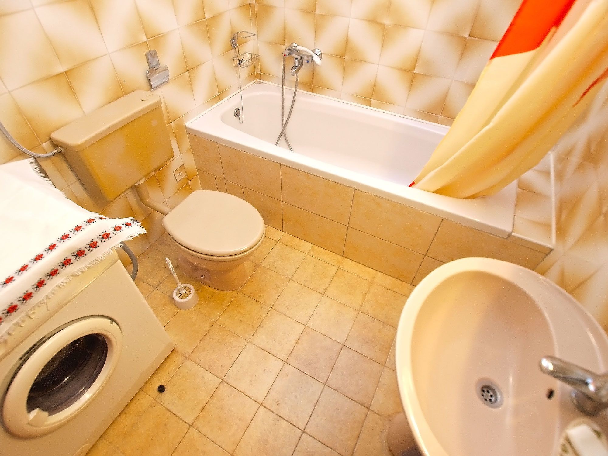 Een badkamer met een toilet, een wasmachine, een bad en een wastafel.