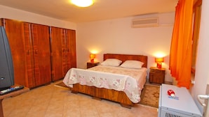 Une chambre à coucher comprenant un lit, une armoire en bois, des lampes de chevet et un radiateur.