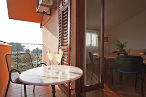 A balcony with a table and chairs, a sliding glass door, and a view of the outdoors.