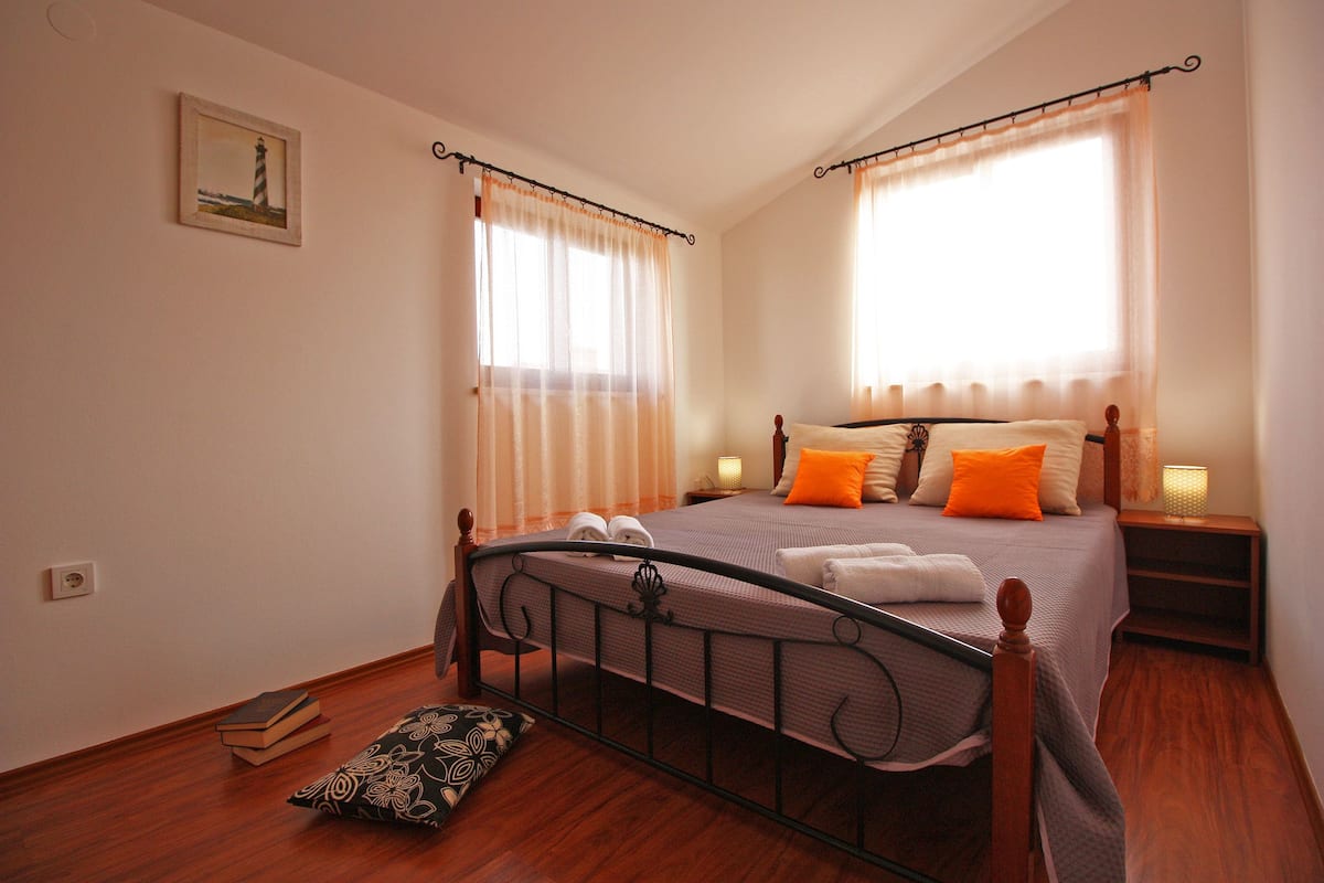 Um quarto bem arrumado com cama, abajures e um quadro na parede.