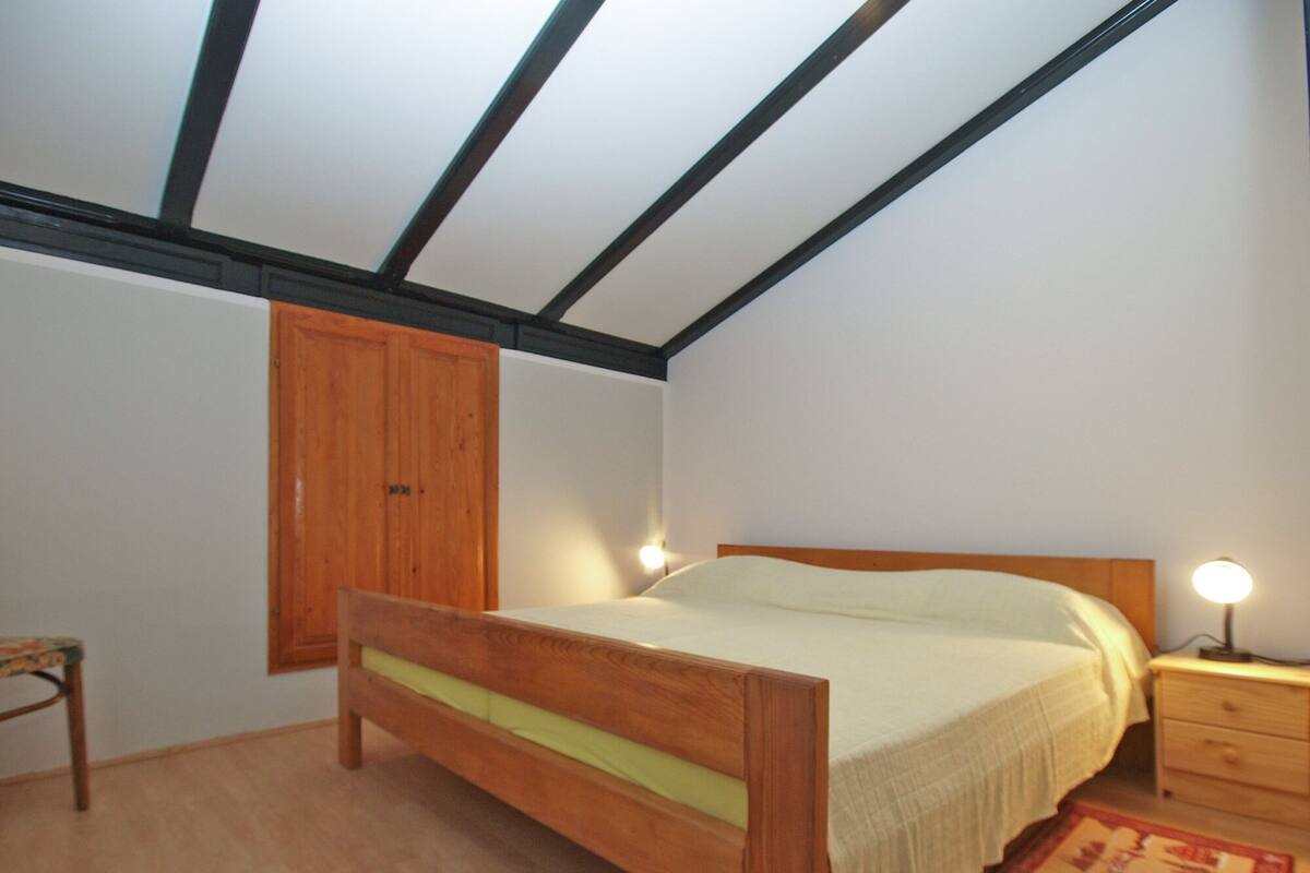 Une chambre à coucher avec un lit en bois, une table de chevet avec une lampe, une armoire en bois et un plancher en bois.