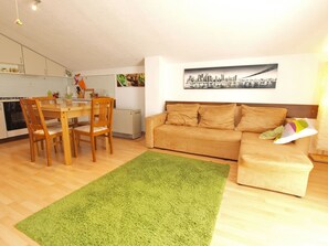 A compact living space with a dining area, a sofa, and a green rug.