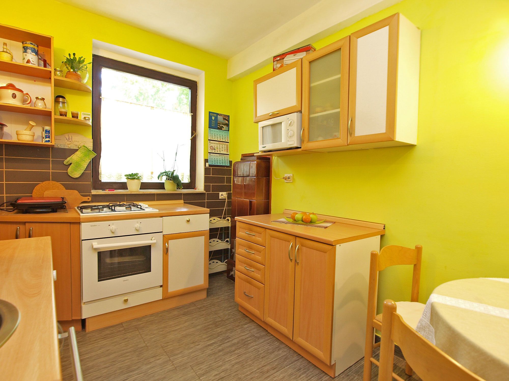 A compact kitchen with wooden cabinets, a gas stove, and a microwave.