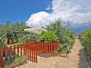 A garden pathway with a wooden fence, a bench, and various plants and flowers. - Apartments Mara 44 (Fazana)