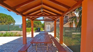 An outdoor covered patio with stone flooring and wooden benches. - Apartments Marina 947 (Fazana)