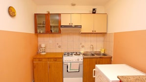 A compact kitchen with wooden cabinets, a gas stove, a sink, and a coffee maker. - Apartments Marina 947 (Fazana)
