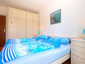Ein Schlafzimmer mit einem Bett, einem Kleiderschrank, einem Nachttisch und einem Bild an der Wand.