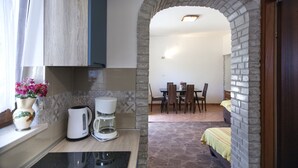 Una cocina con cafetera, hervidor y un florero con flores sobre la encimera.