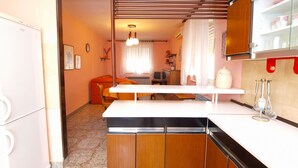 Une cuisine de taille réduite avec un îlot central, des meubles en bois et un plan de travail blanc.