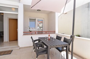 Un balcon avec une table et des chaises, une bouteille de vin et une plante en pot.