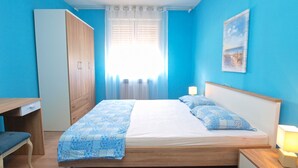 Une chambre à coucher comprenant un lit, une table de chevet, une lampe, une armoire et un bureau avec une chaise.