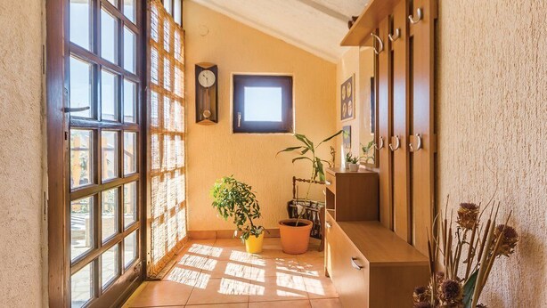 A sunlit hallway with large windows, a clock, and potted plants. - Apartments Luce 1204 (Medulin)