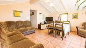 A cozy living room with a sofa set, a dining table with chairs, a TV, and a plant. - Apartments Luce 1204 (Medulin)