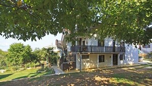 A two-story house with a balcony, surrounded by greenery and trees. - Apartments Luce 1204 (Medulin)