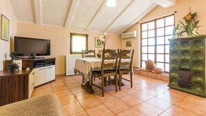 A cozy dining area with a table and chairs, a television, and a cabinet with a plant. - Apartments Luce 1204 (Medulin)