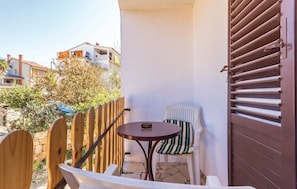A small outdoor patio with a round table and two chairs, a wooden fence, and a view of neighboring houses. - Apartments Luce 1204 (Medulin)
