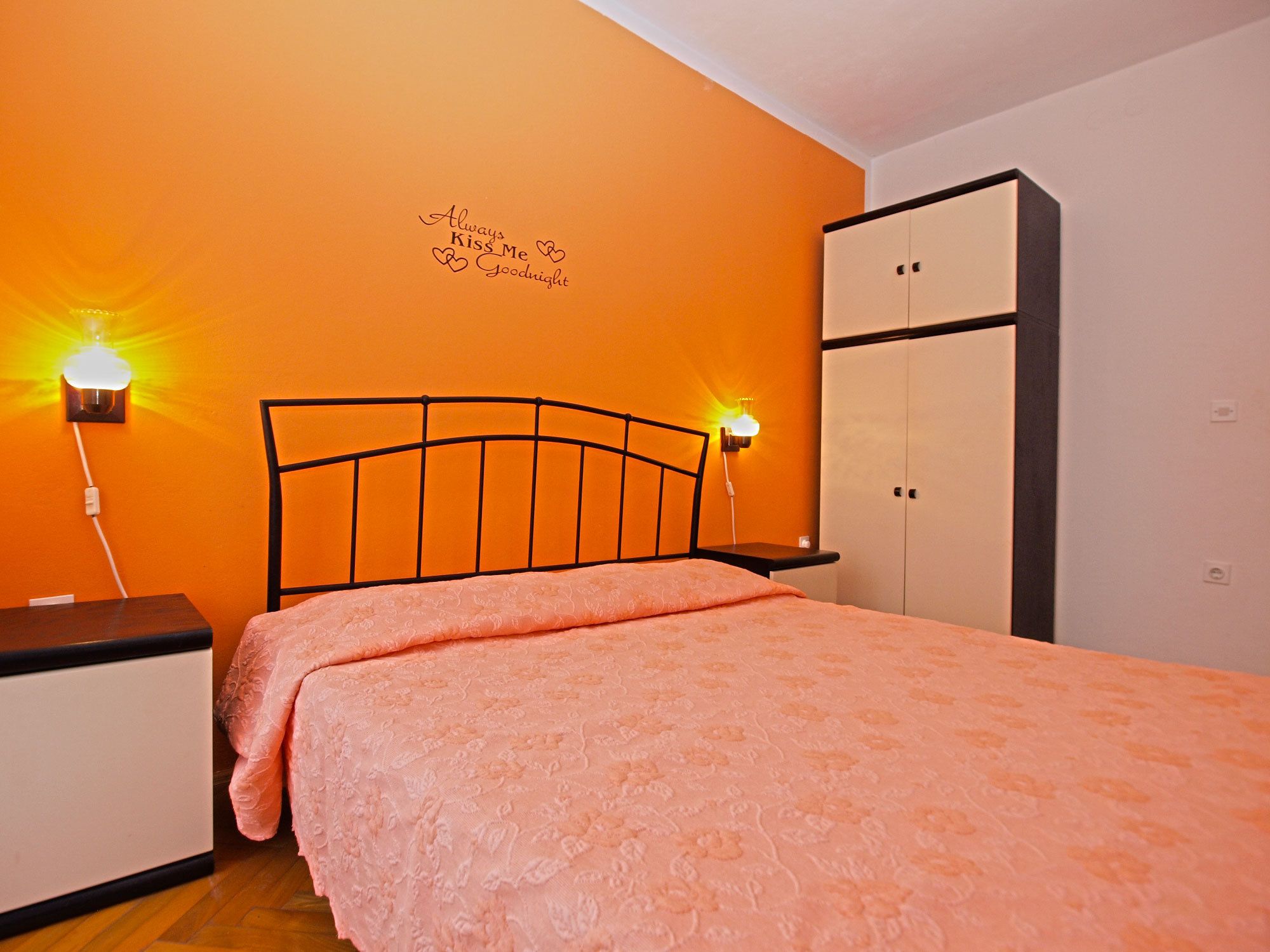 Een slaapkamer met een bed, een kledingkast en twee wandlampen.