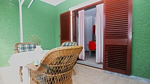 Een kamer met een groene, gestructureerde wand, een witte tafel met een rieten stoel, en een rode stoel.