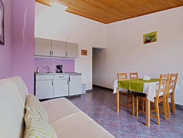 A compact living space with a kitchenette, a dining area, and a sofa.