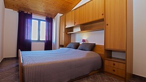 Een slaapkamer met een bed, een houten garderobe en een raam met gordijnen.